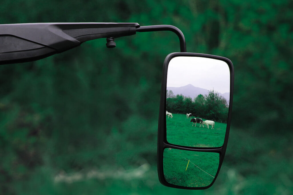 specchio retrovisore applicato a trattore dove si riflette un ambiente naturale